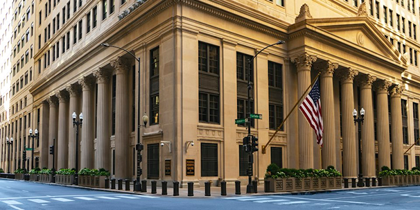 Columned bank building on a city corner with an American flag